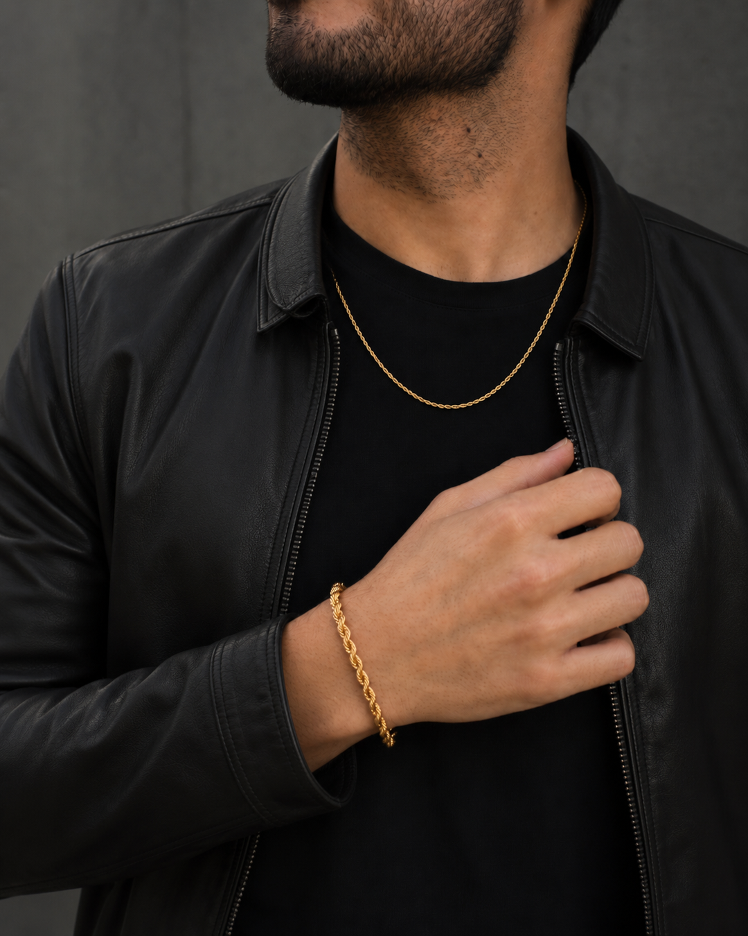 Hombre con chaqueta de cuero negro usando collar y pulsera de cadena dorada